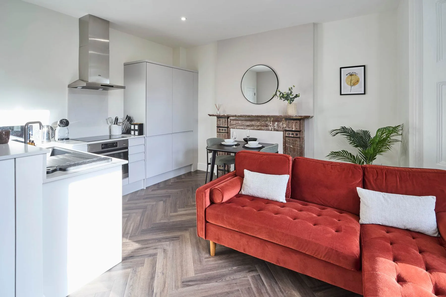 A bright open-plan living room and kitchen with a red sofa and dining table.