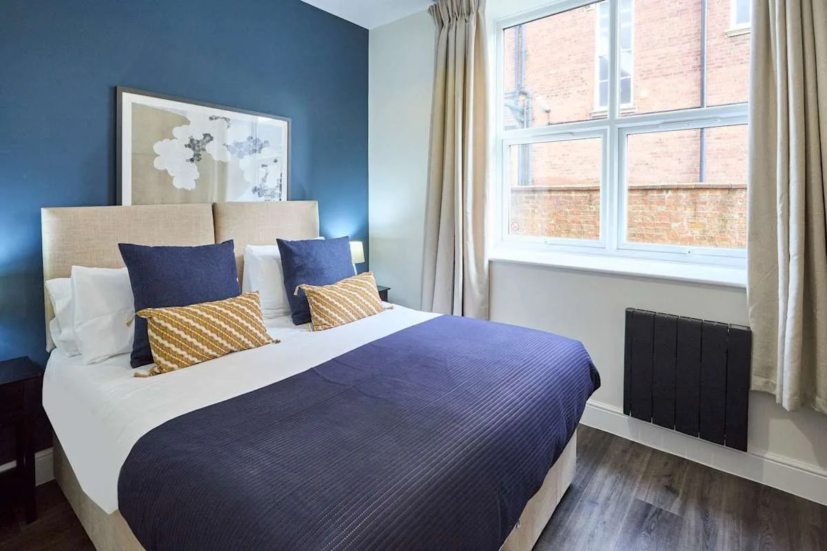A bedroom with a neatly made bed beside a large window.