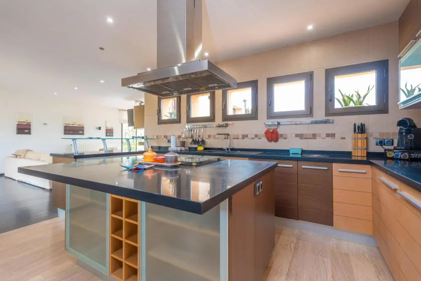 A spacious kitchen with a central island, dark countertops, and windows above the work area.