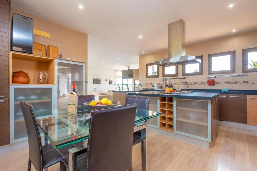 A modern kitchen with a glass dining table and counter seating.