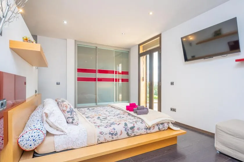 A bedroom with a low bed and sliding wardrobe doors.