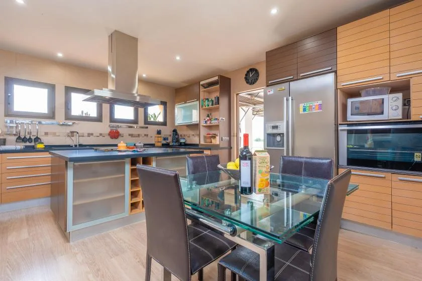 A modern kitchen with a glass dining table and stainless steel appliances.