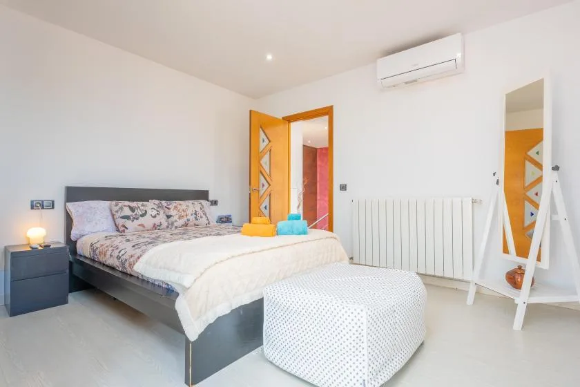 A bright bedroom with a bed and a white upholstered bench.
