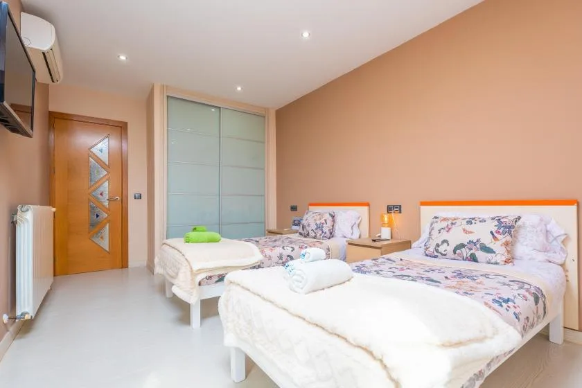 A bedroom with two beds, floral bedding, and a sliding wardrobe.