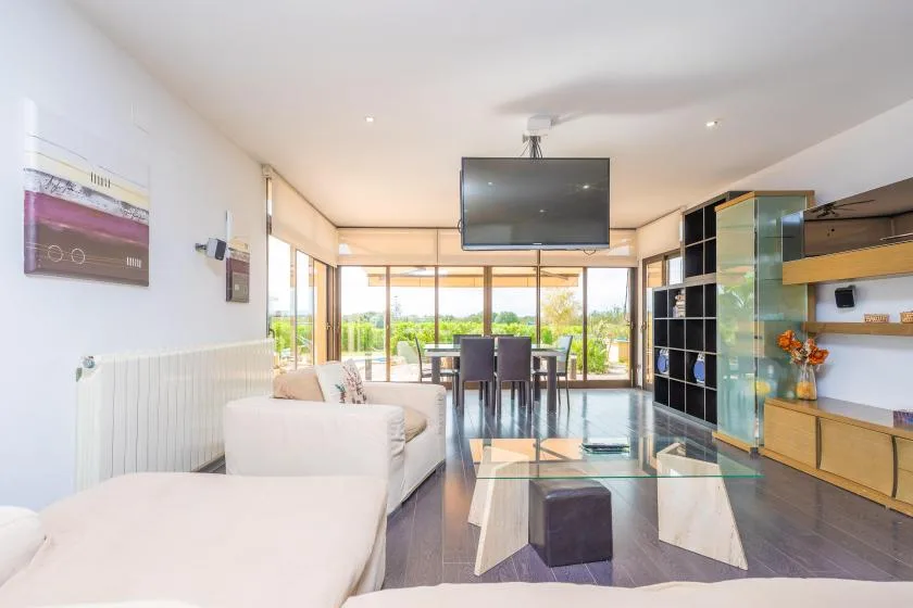 A bright living and dining area with seating, a table, and wide windows.