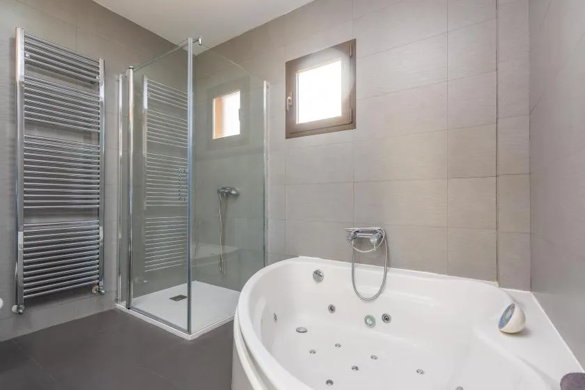 A tiled bathroom with a glass shower and a large whirlpool bathtub.