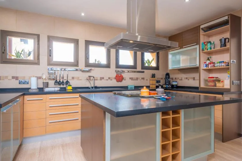A modern kitchen with a central island and open shelving.