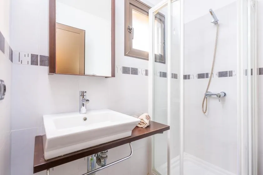 A bright bathroom with a sink and a glass-enclosed shower.