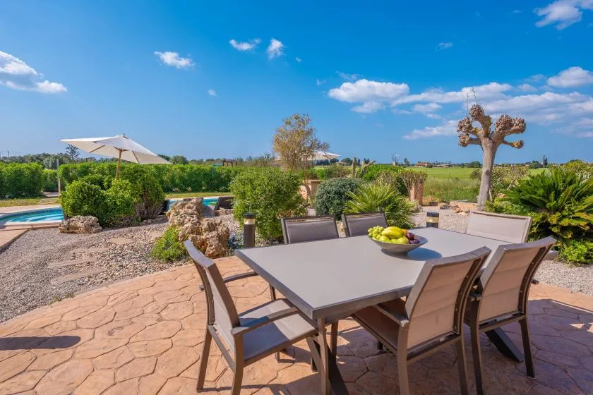 A patio dining area overlooks a garden and swimming pool.