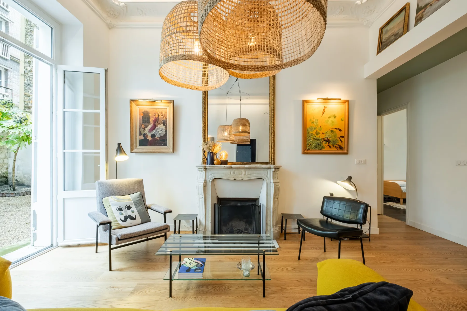 A bright living room with a fireplace, seating, and woven pendant lights.