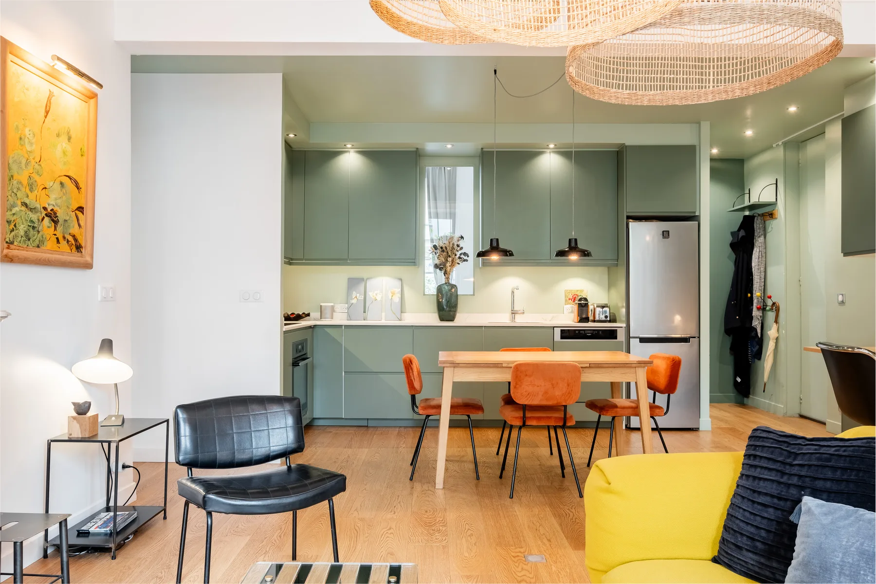 A bright open-plan kitchen and dining area with a table and colorful seating.