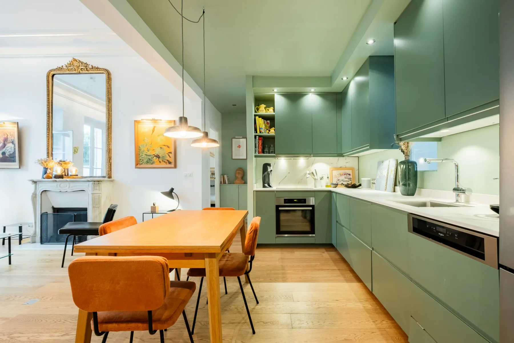 An open kitchen and dining area with green cabinets and a wooden table.