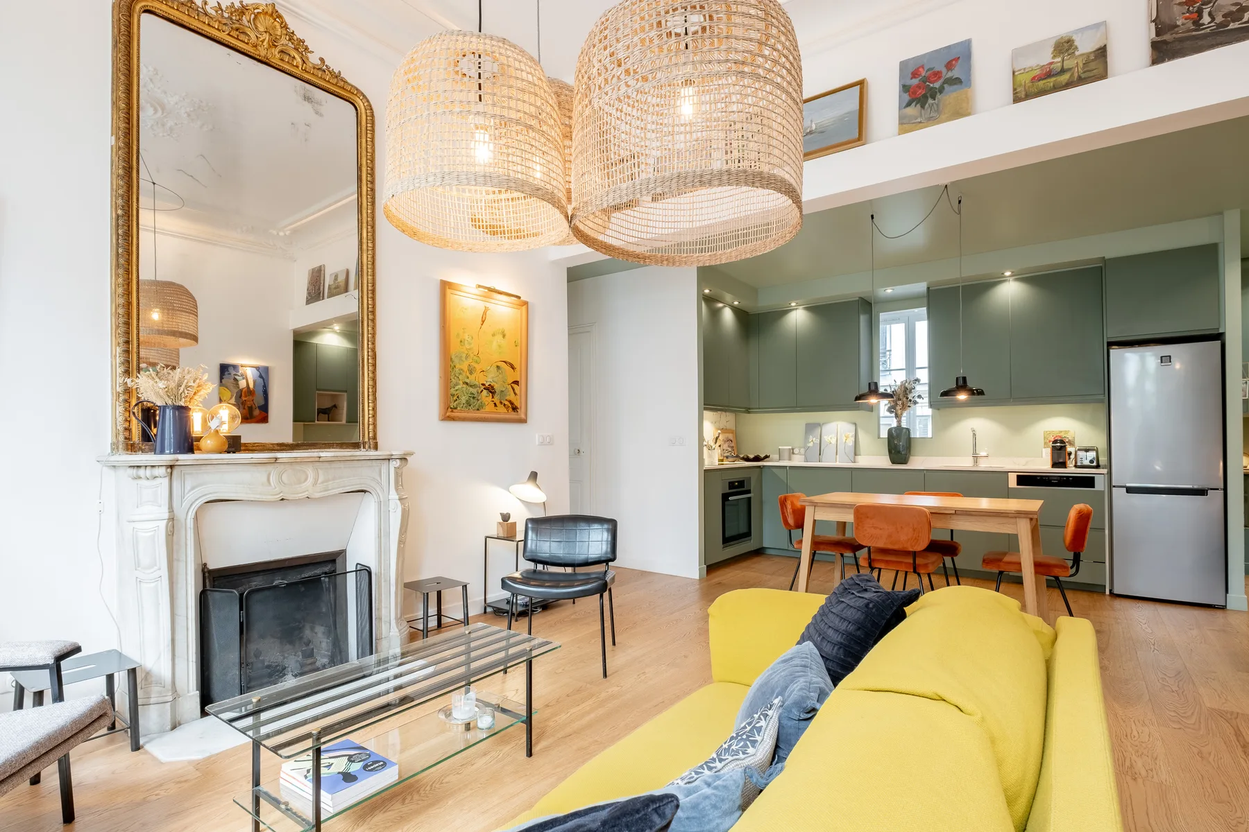 A bright living room opens into a kitchen and dining area, with a yellow sofa.