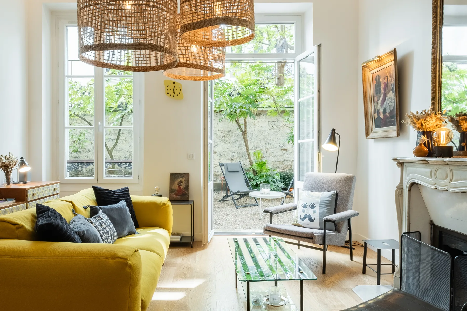 A bright living room with yellow seating, a glass coffee table, and an open patio door.