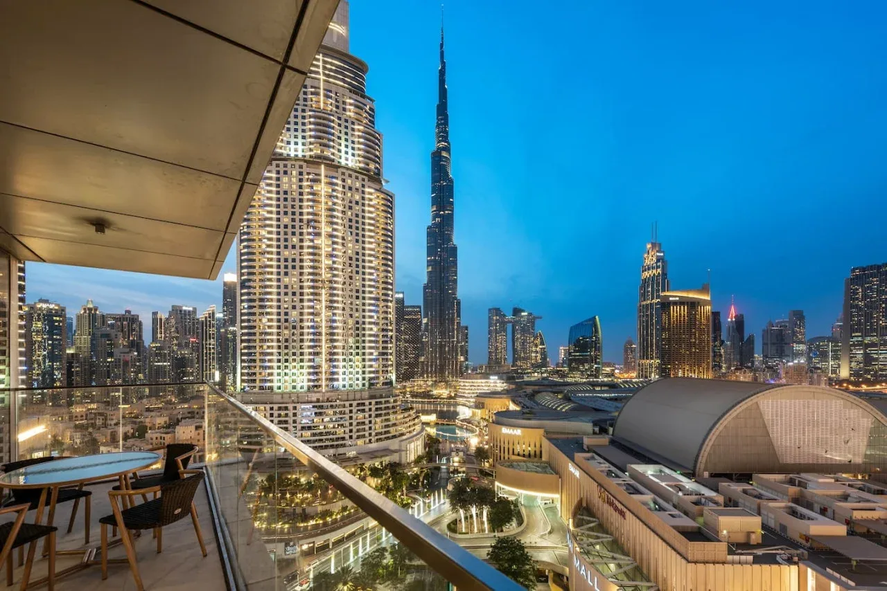 Un balcón ofrece vistas de un horizonte urbano iluminado al anochecer.