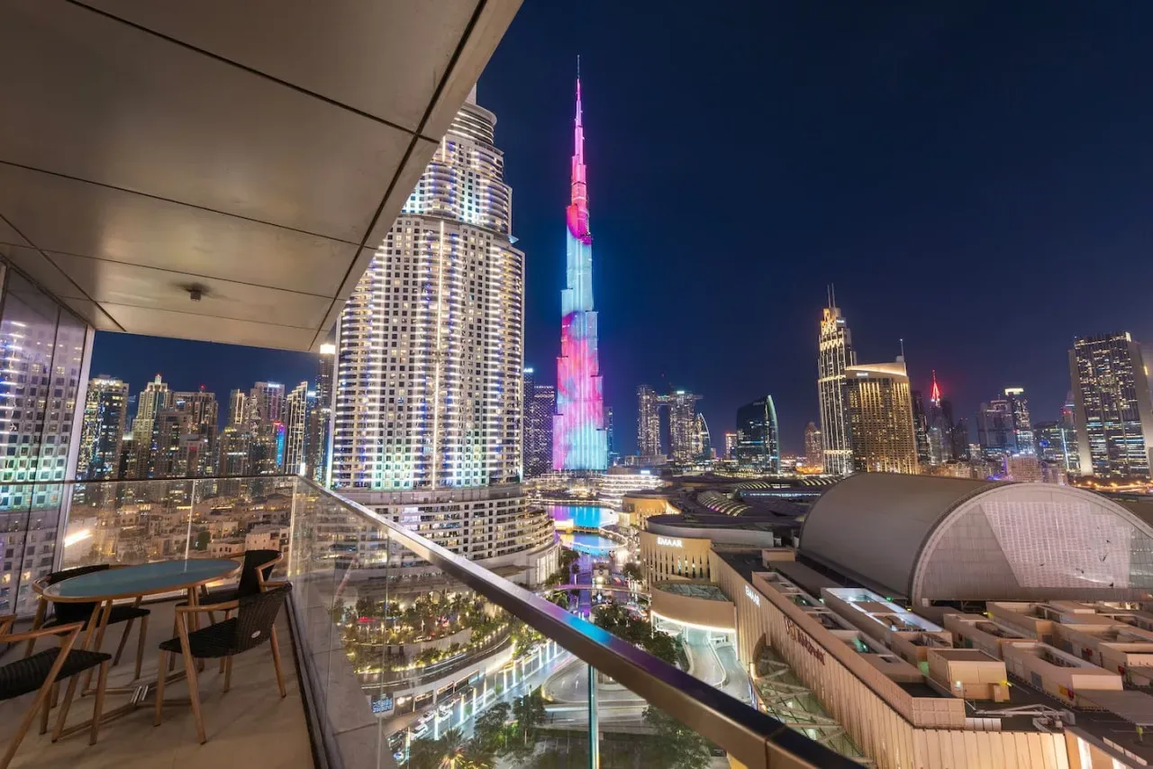 A balcony overlooks a brightly lit city skyline at night.