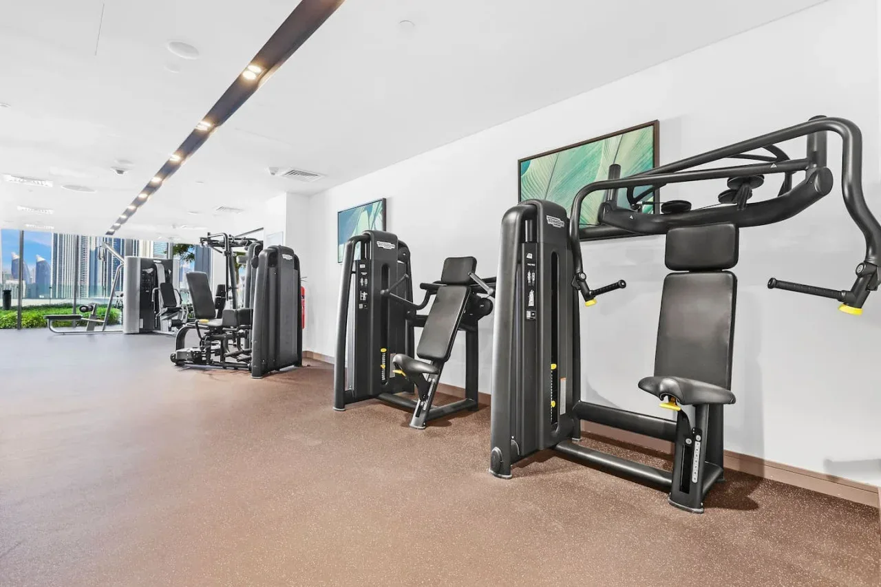 Un gimnasio con máquinas de ejercicio dispuestas junto a las paredes.