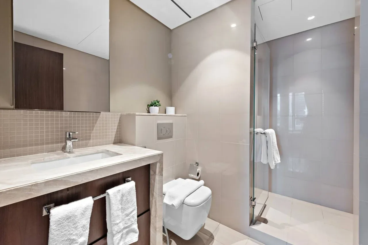 Un baño moderno con lavabo, inodoro y ducha con mampara de vidrio.