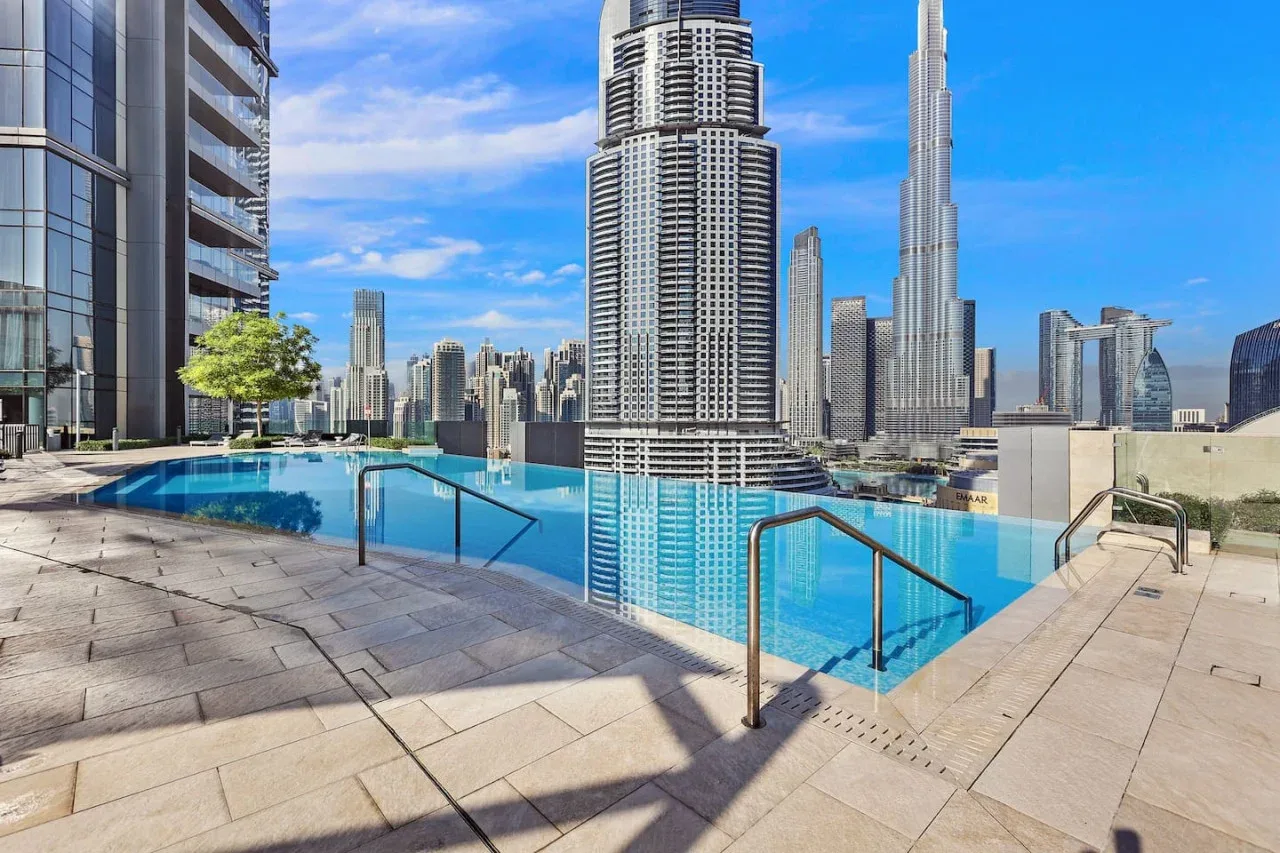 Una piscina en la azotea ofrece vistas del horizonte urbano bajo un cielo azul despejado.
