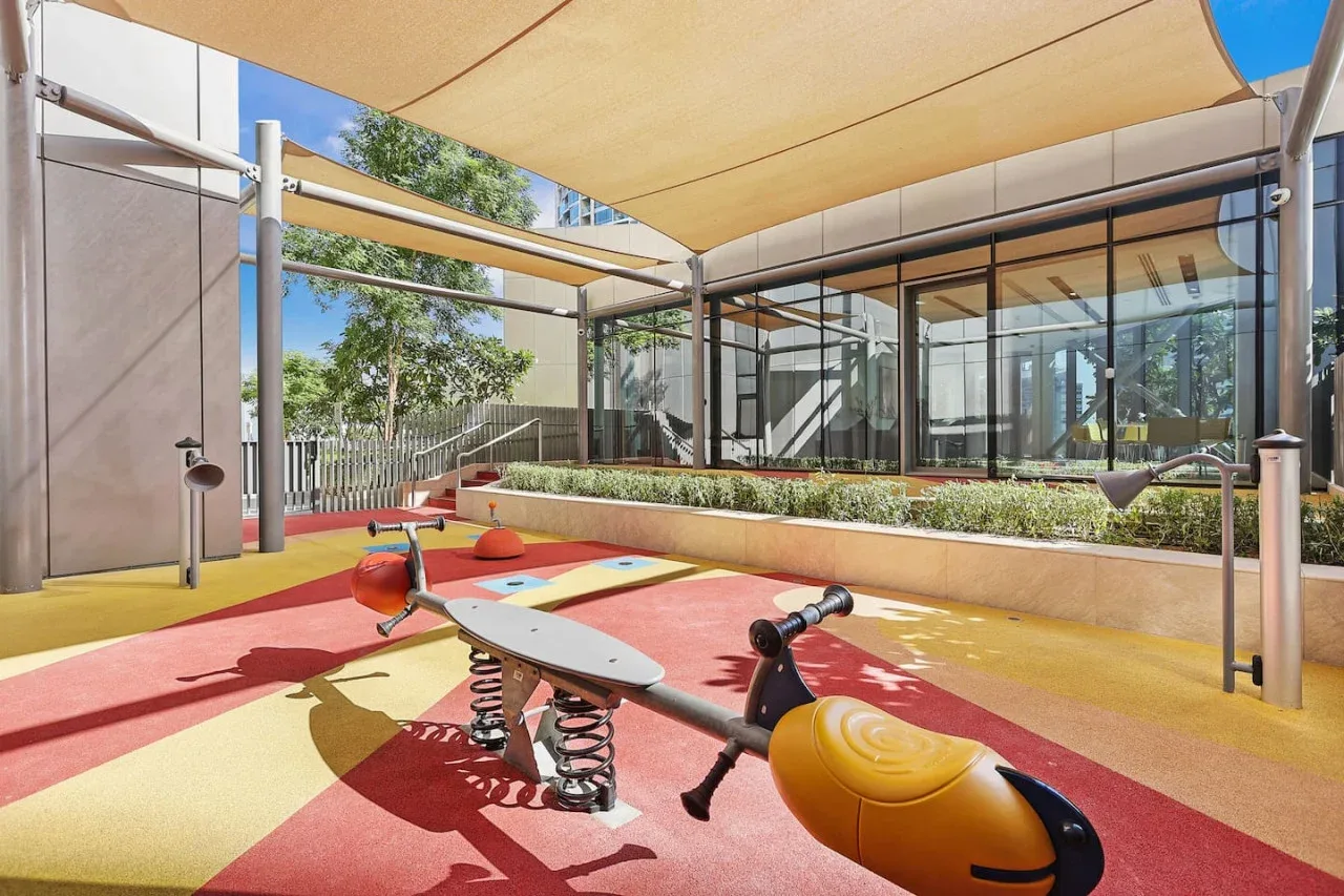 Un parque infantil al aire libre con suelo de colores y juegos de muelles.
