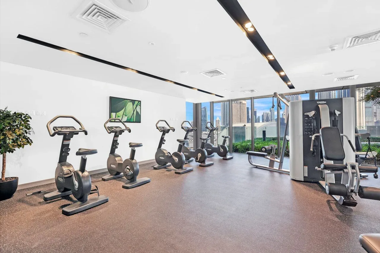 Un gimnasio luminoso con bicicletas estáticas, máquinas de pesas y grandes ventanales.