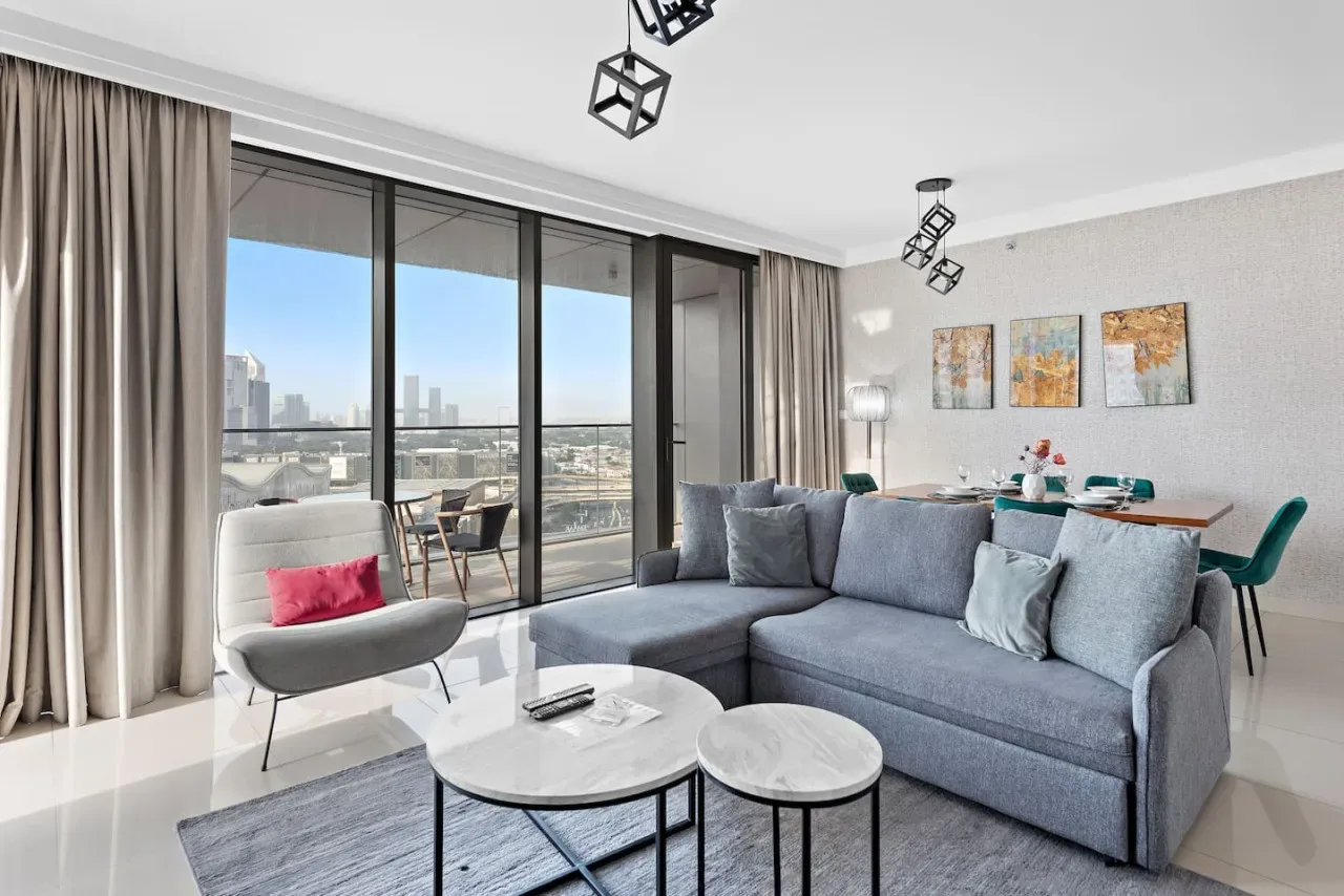 Una sala luminosa con asientos grises junto a grandes ventanales con vistas a la ciudad.