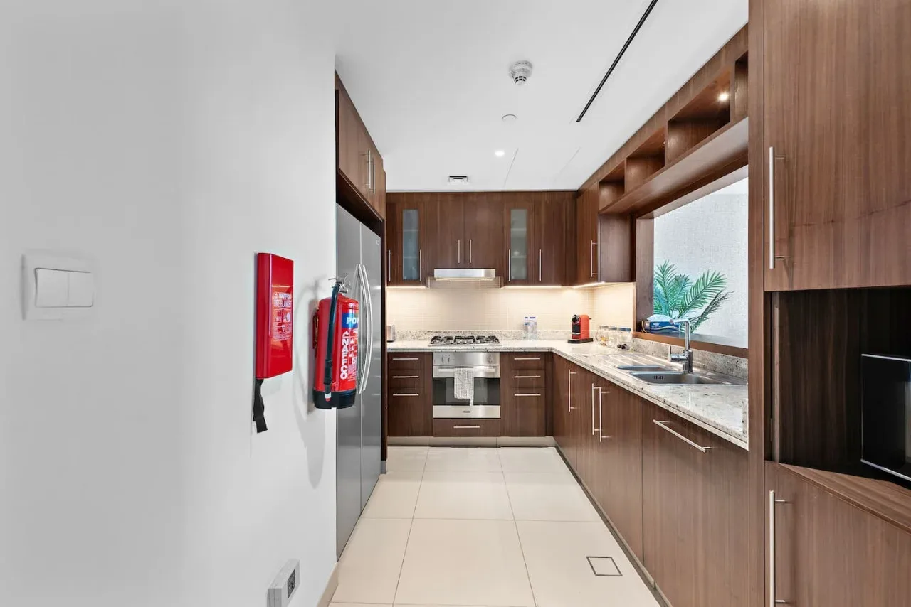 Una cocina moderna con gabinetes de madera, encimeras claras y electrodomésticos integrados.