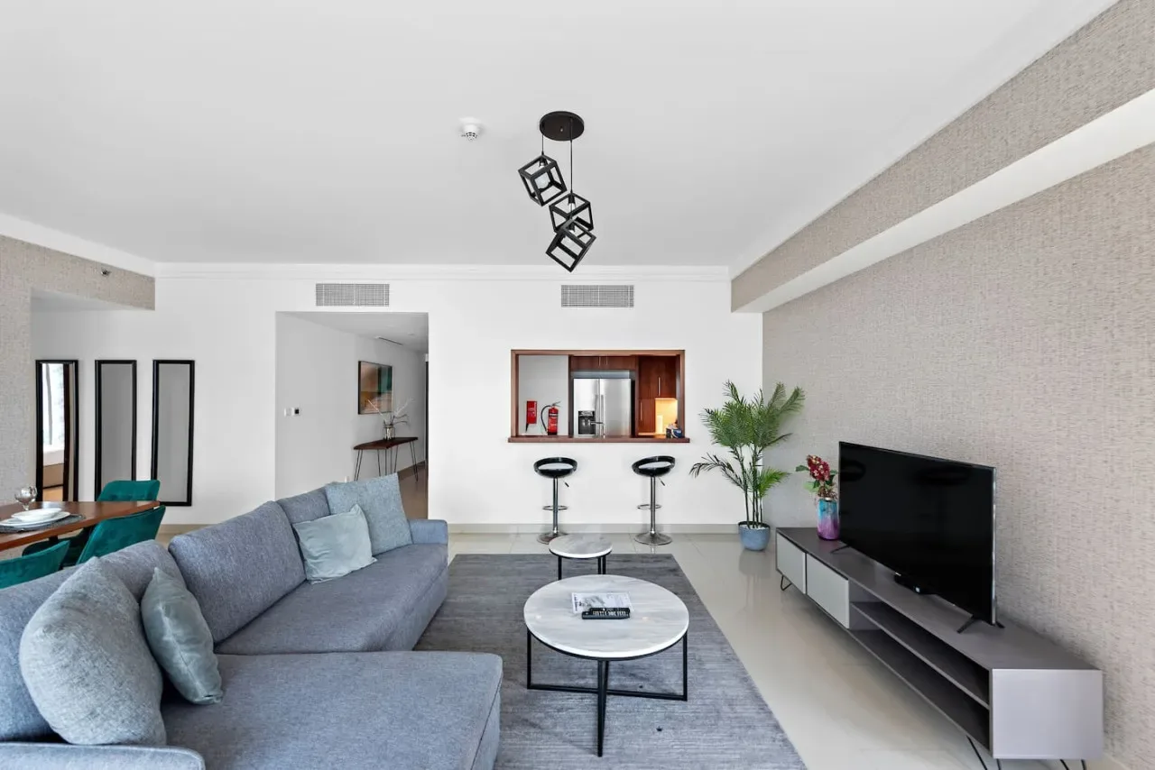 Una sala luminosa con asientos, una mesa de centro y un televisor.