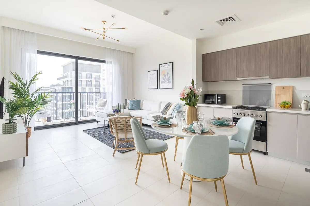 A bright open-plan living and dining area with a kitchen and balcony doors.
