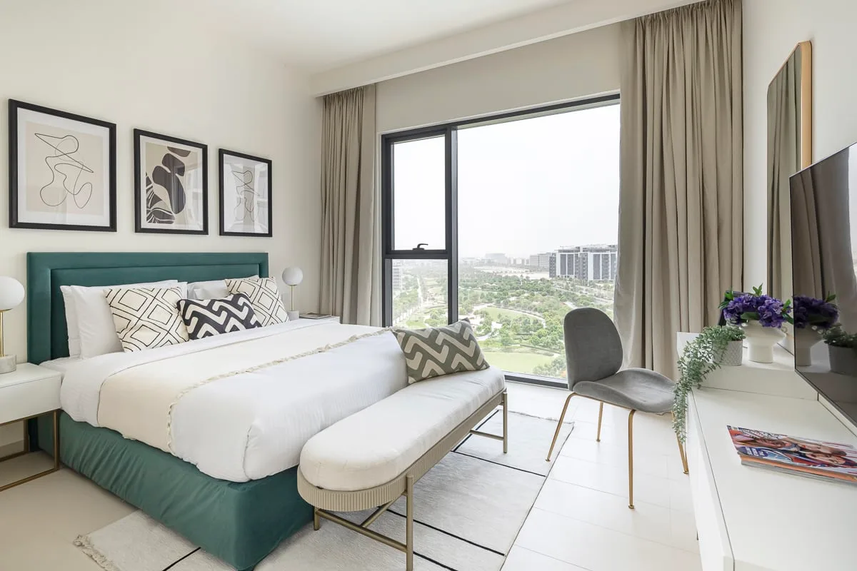 Un dormitorio luminoso con una cama, una ventana amplia y vistas a zonas verdes.