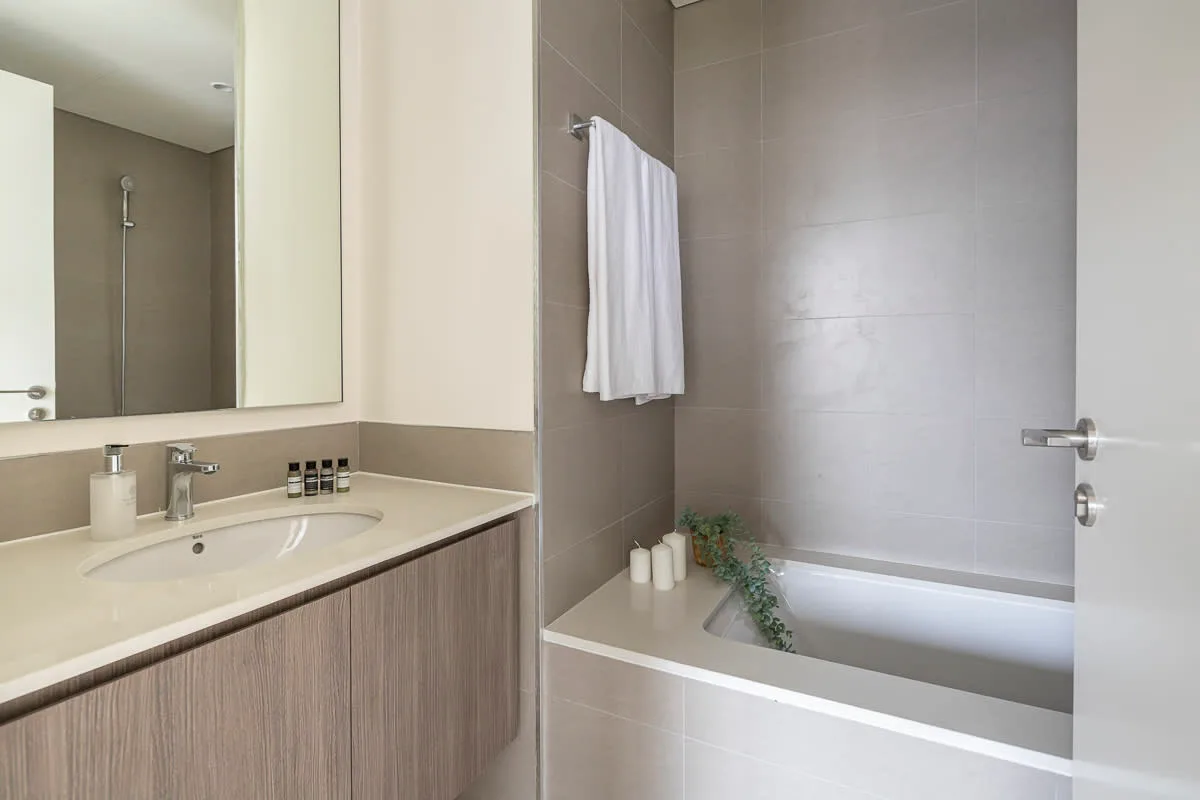 Un baño con lavabo y bañera, y una toalla colgada en la pared.