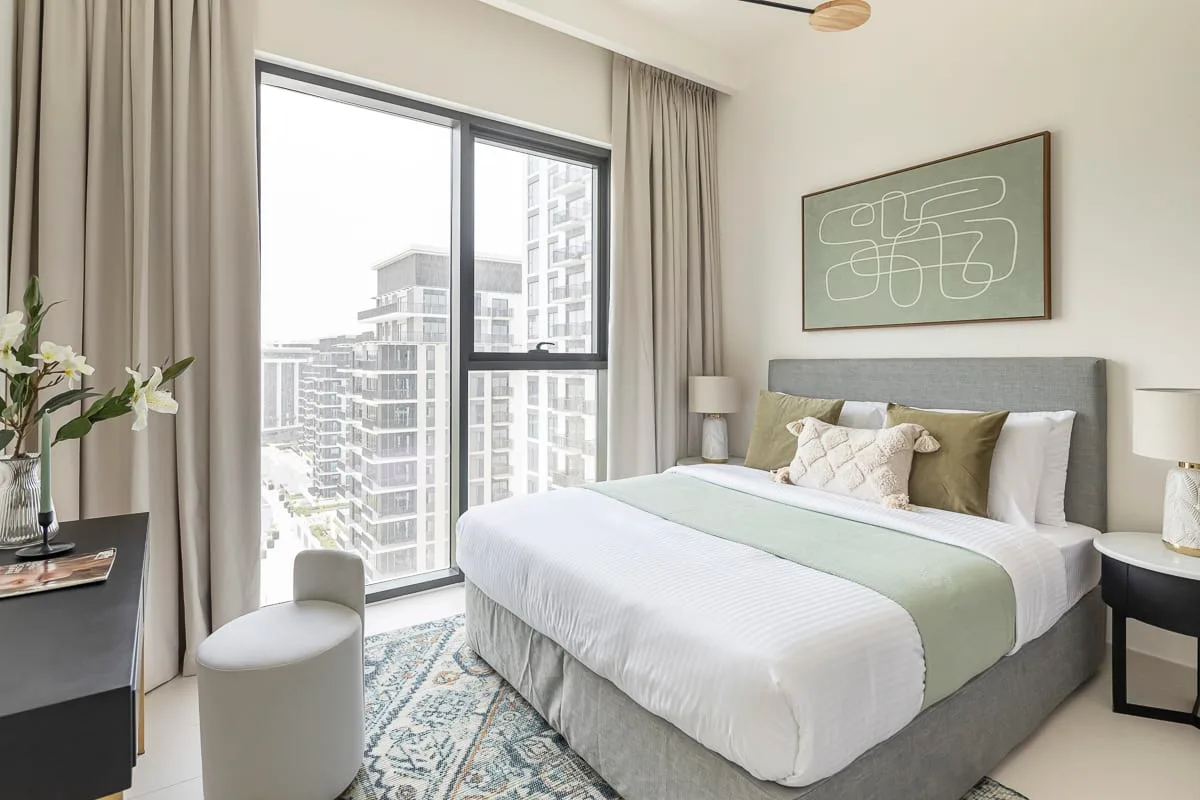 Un dormitorio luminoso con una cama grande junto a ventanas de piso a techo.