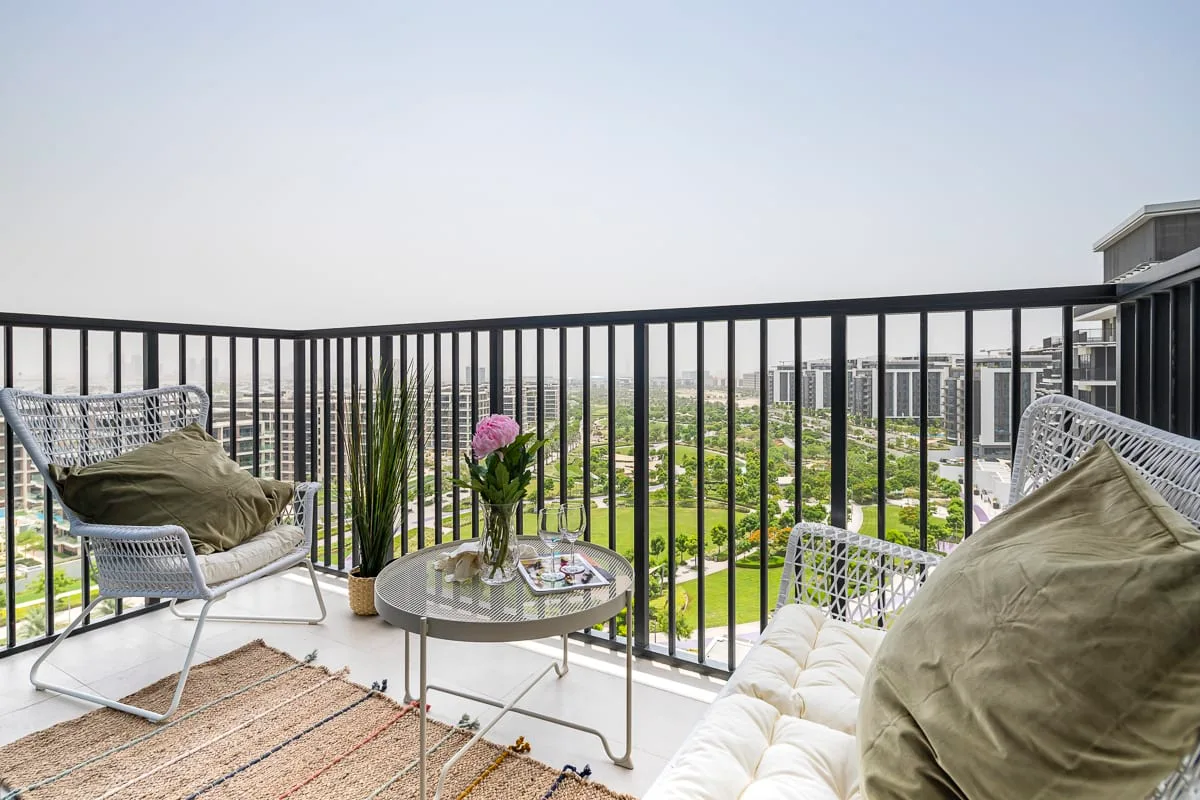 Una zona de estar en el balcón da a un horizonte urbano, con plantas y una mesa pequeña.