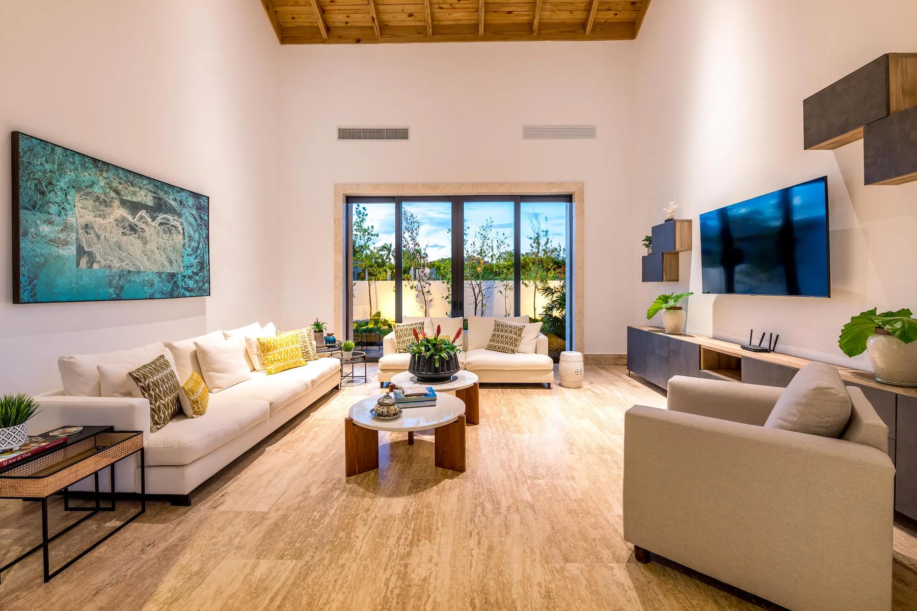 A bright living room with seating, a coffee table, and glass doors opening to a patio.