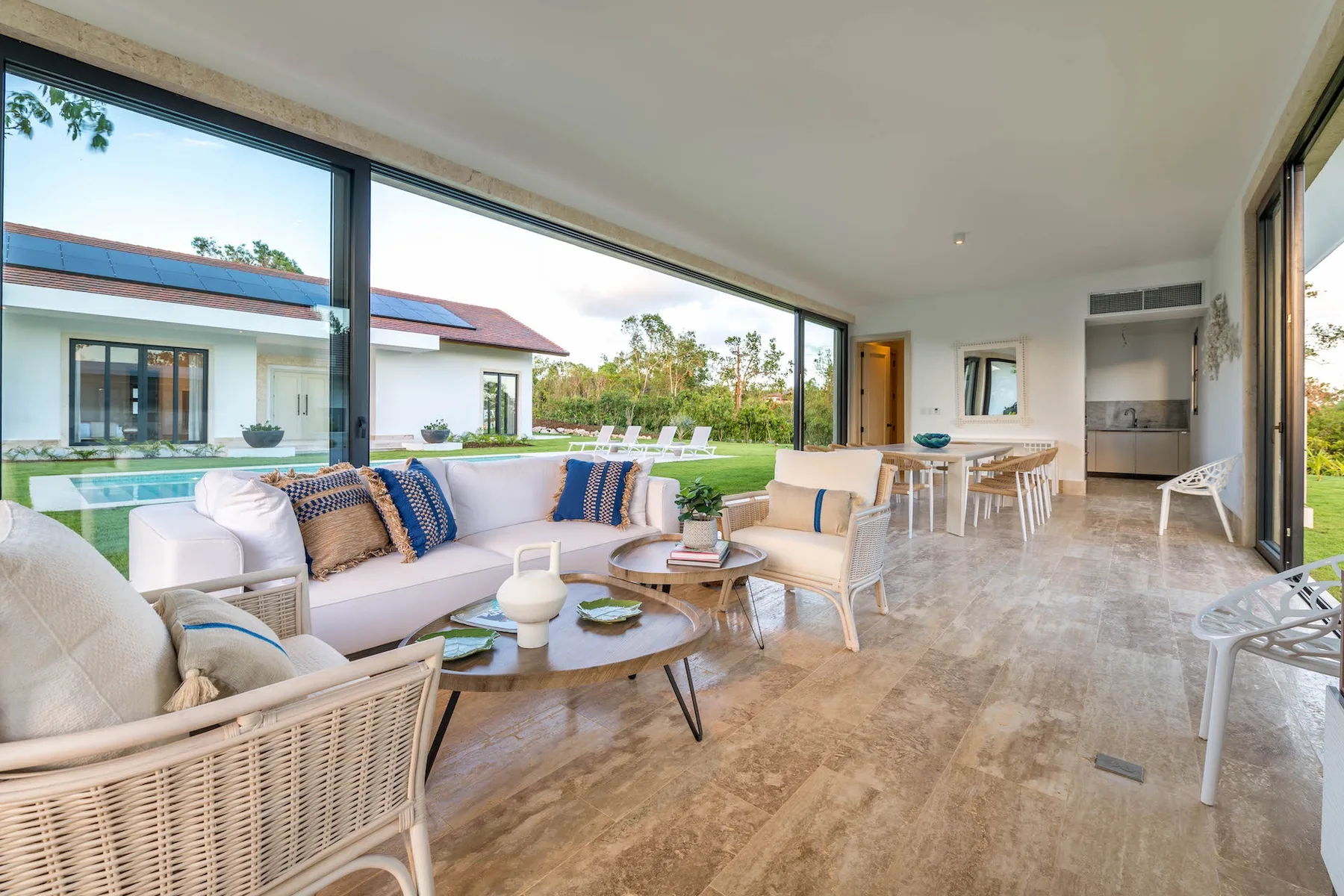 A bright living and dining area opens onto a lawn through large glass doors.