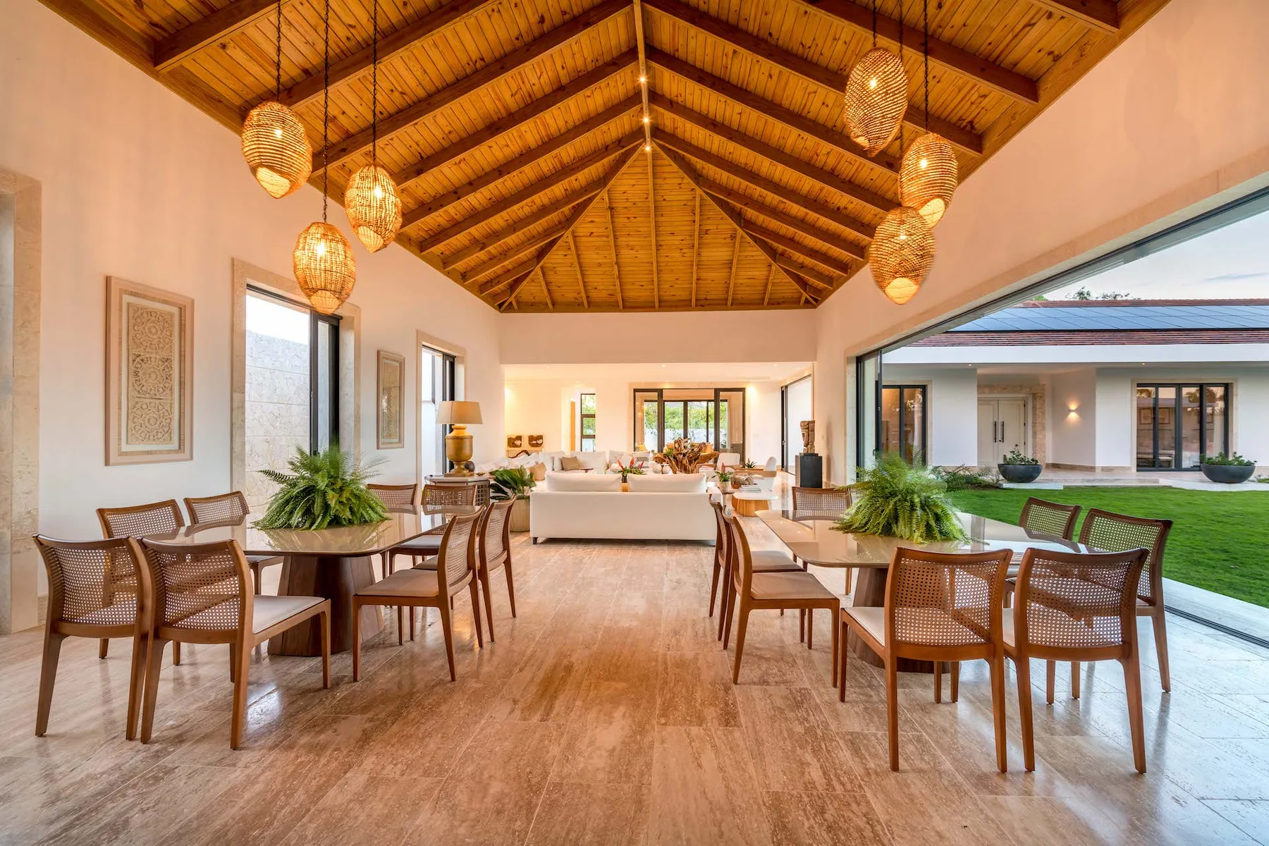Un amplio comedor y sala de estar con techo de vigas de madera y grandes ventanales.