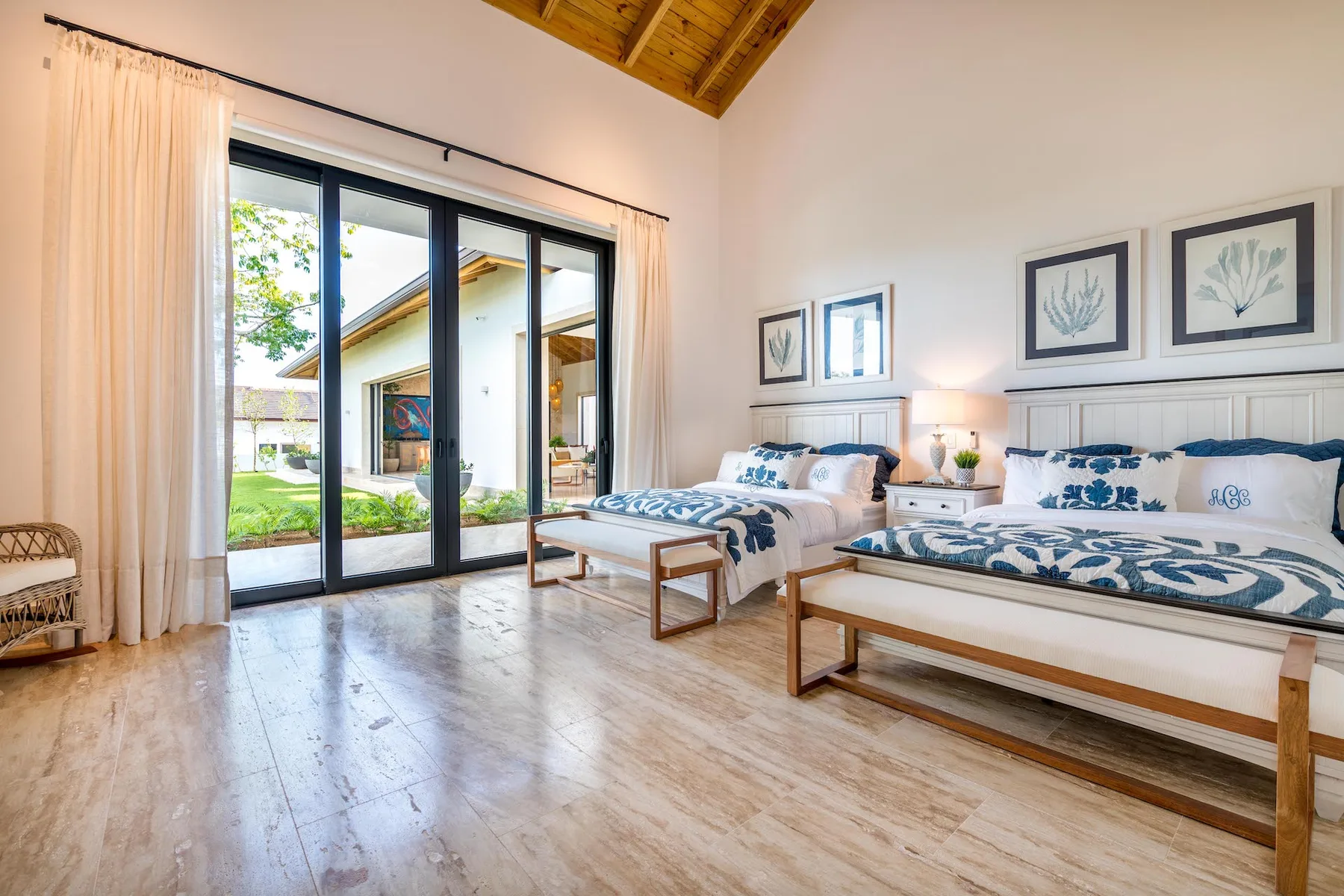A bright bedroom with two beds and large glass doors.
