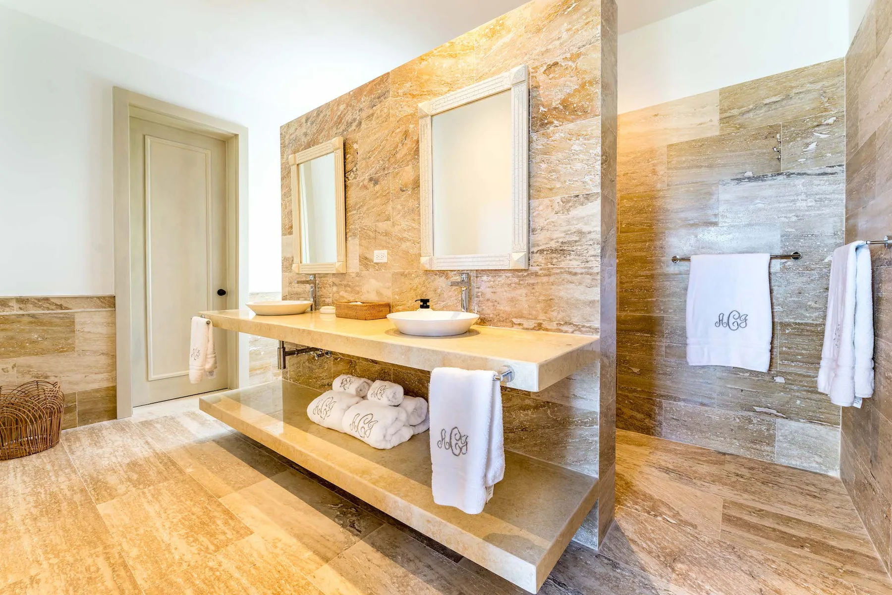 A bright bathroom with a double vanity and a shower area.