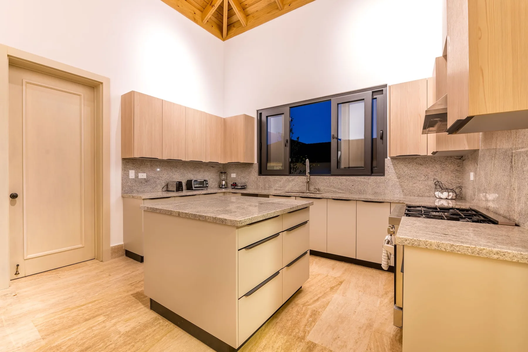 A bright kitchen with a central island and wooden cabinets.