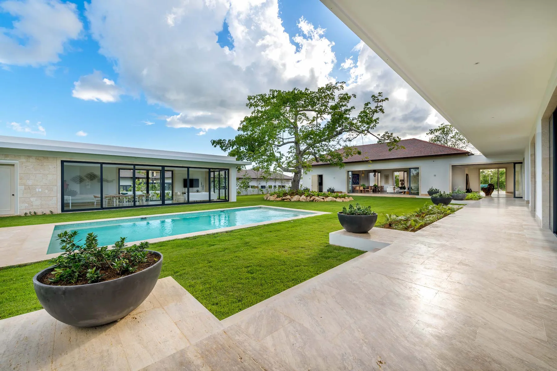 A landscaped courtyard with a long swimming pool beside a modern building.