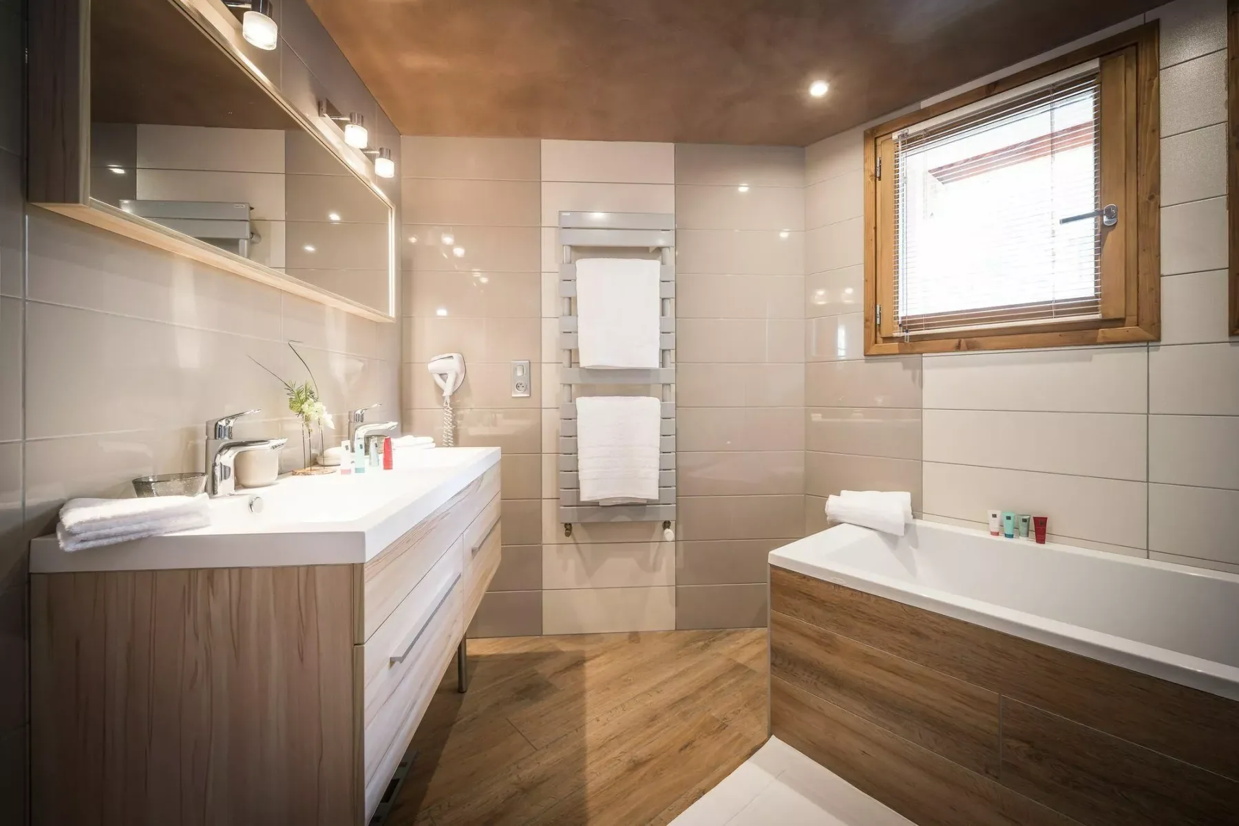 A bathroom with a vanity, bathtub, and window.