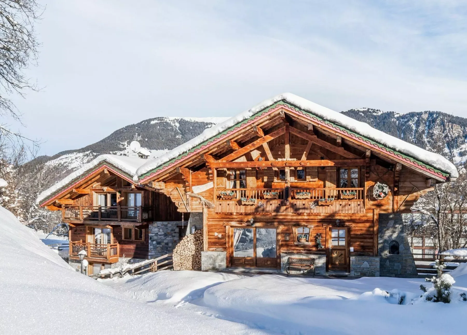 A large wooden chalet stands in a snowy mountain landscape.