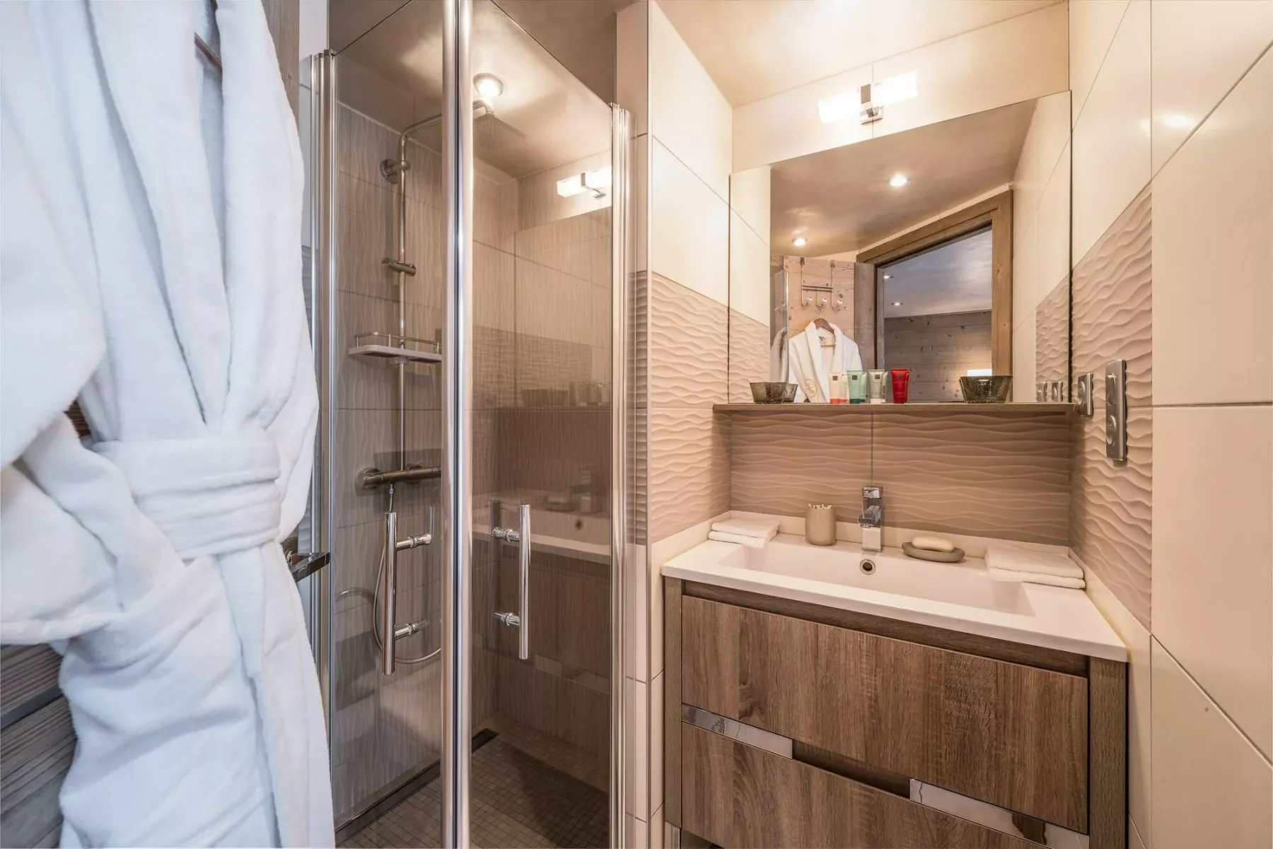 A bathroom with a glass shower and a sink vanity.