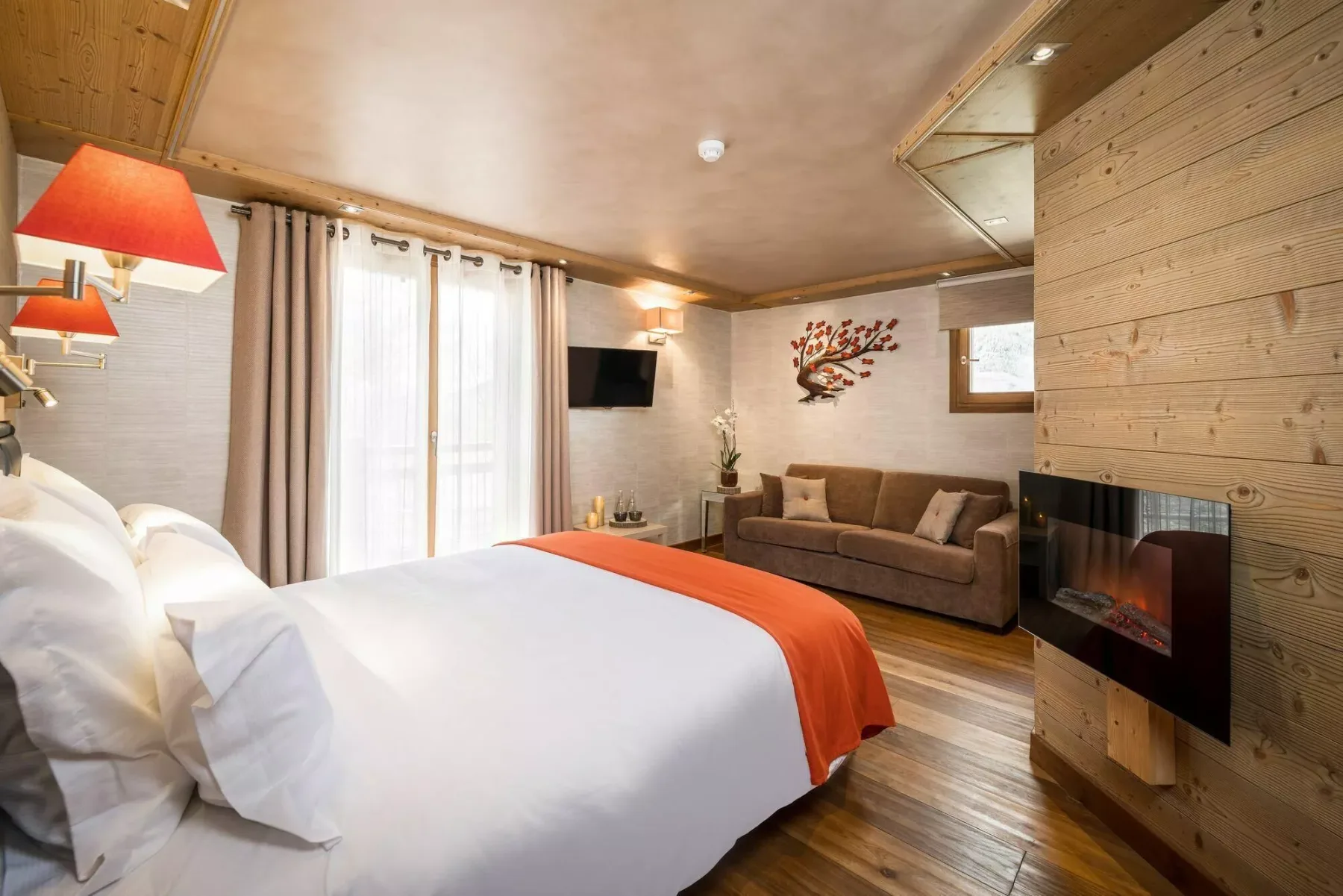 A bedroom with a large bed, a sofa, and a wall-mounted television.