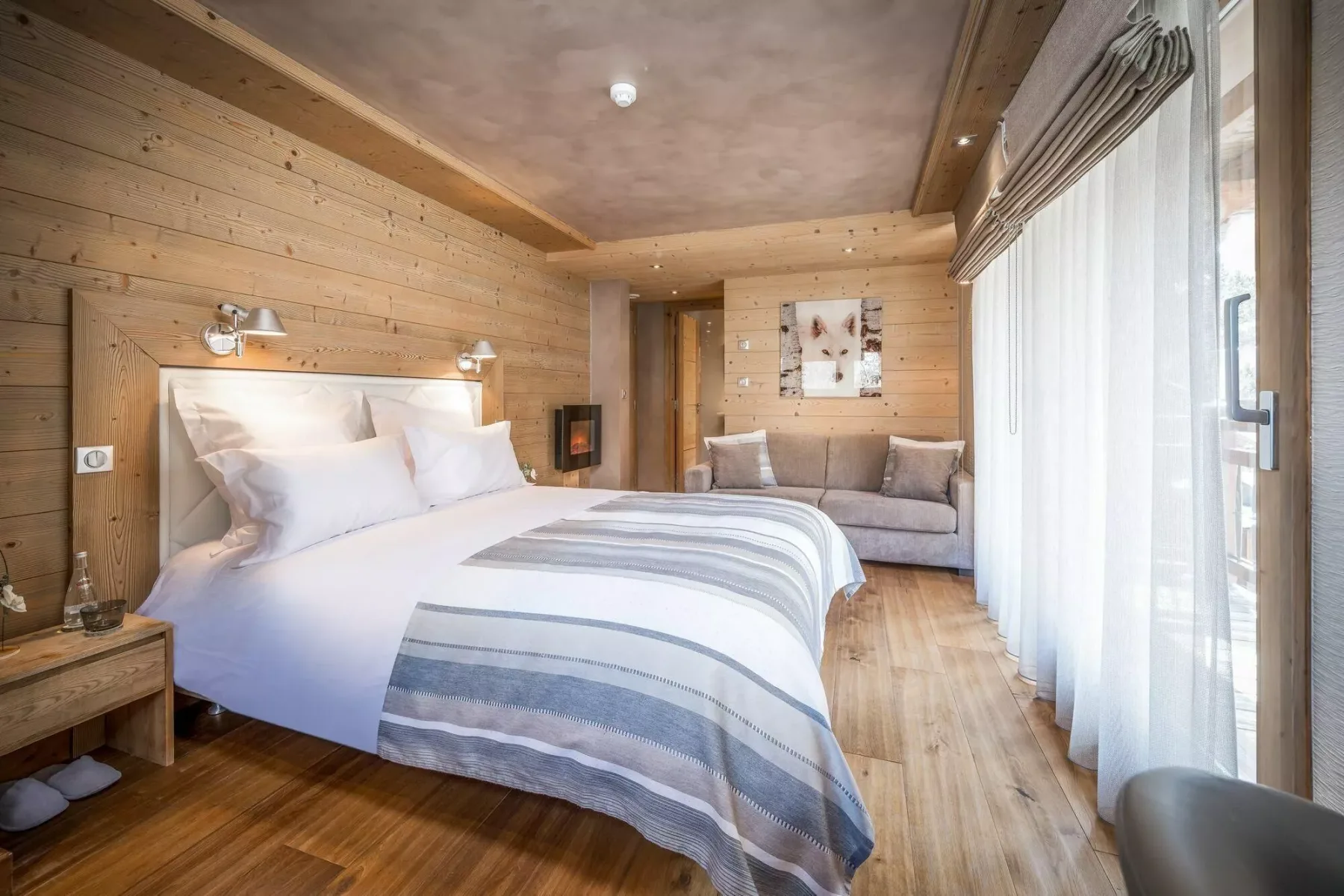 A wood-paneled bedroom with a neatly made bed and a small seating area.