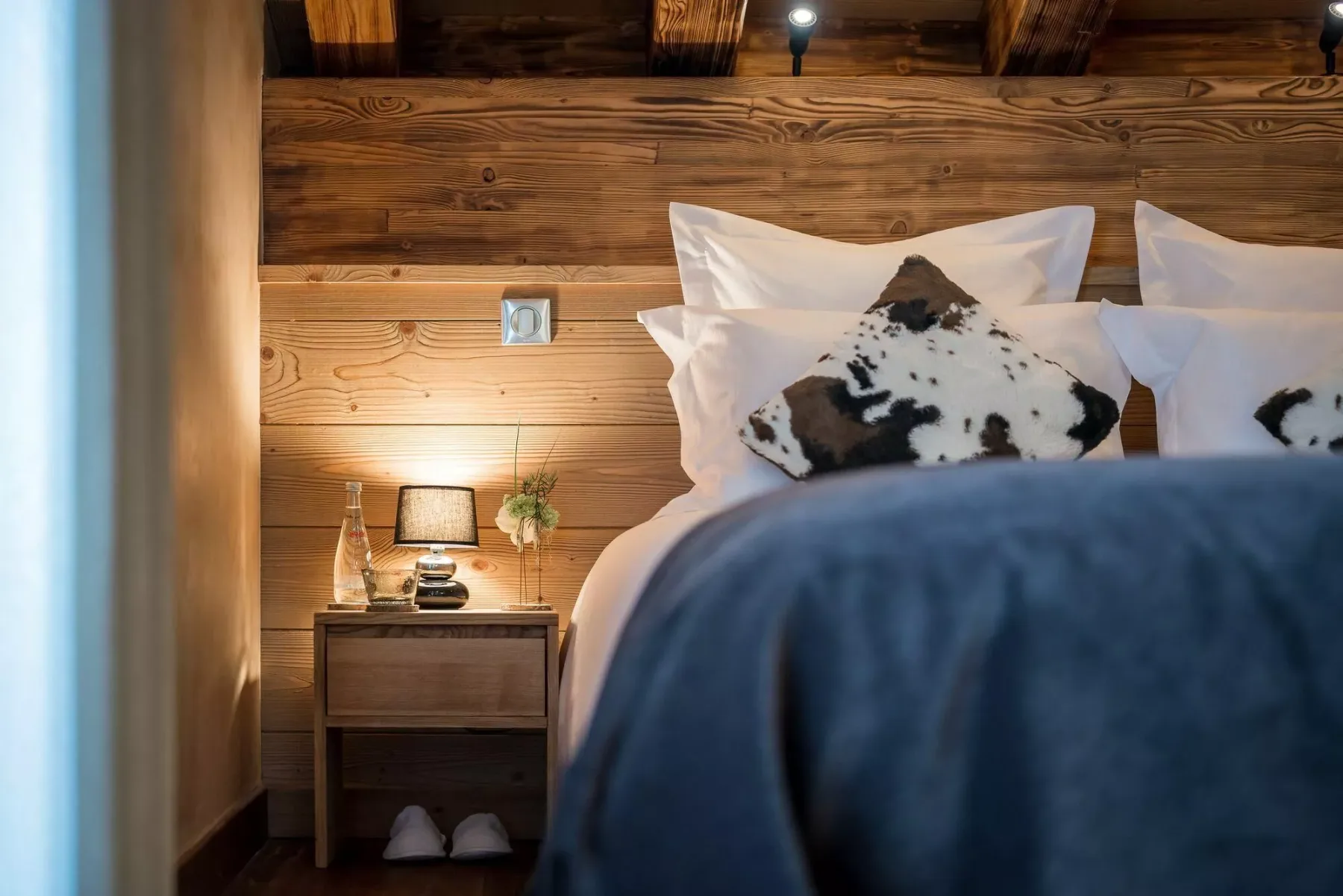 A bedroom with a wooden headboard, white pillows, and a bedside table.