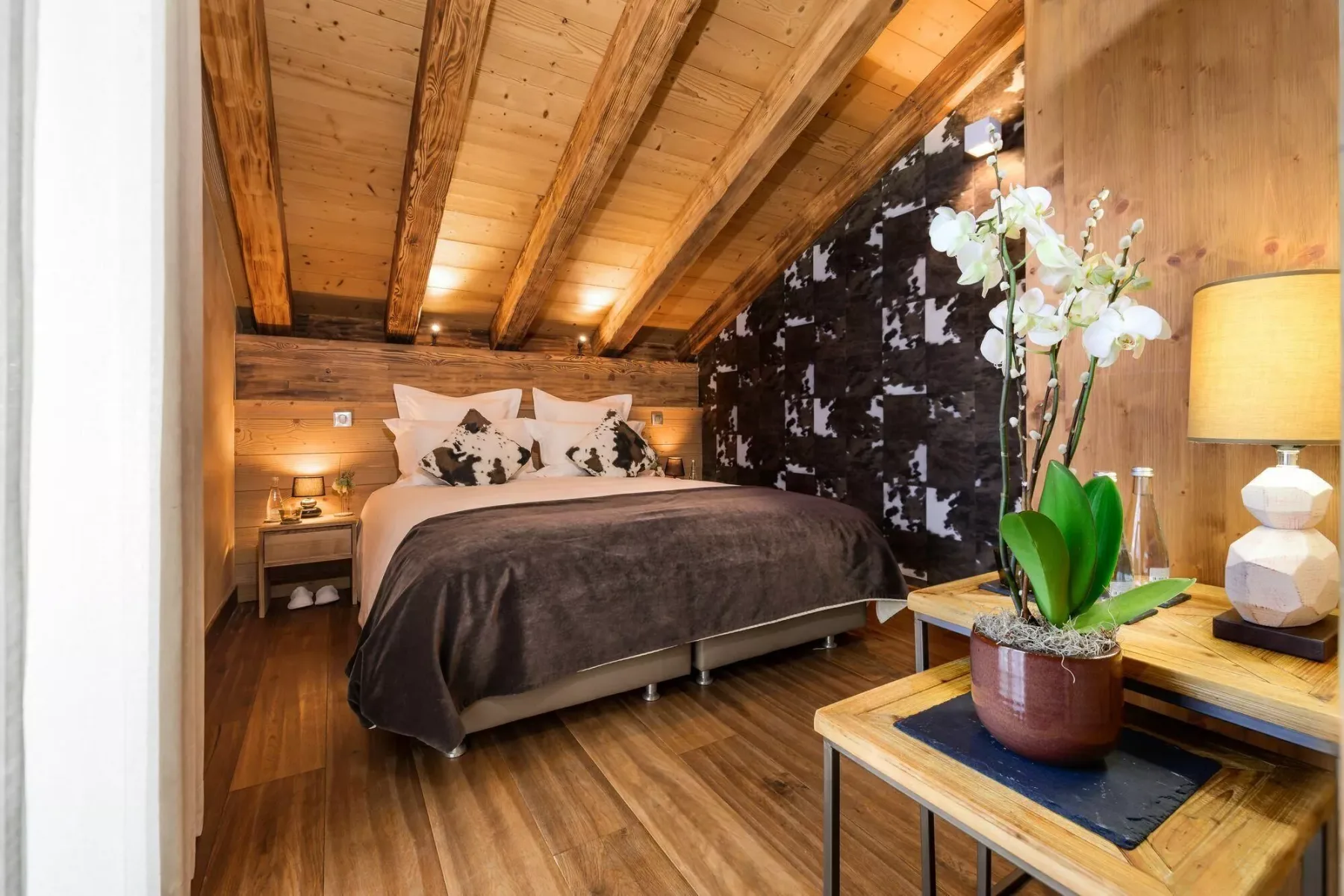 A bedroom with a large bed beneath a wood-beamed ceiling.