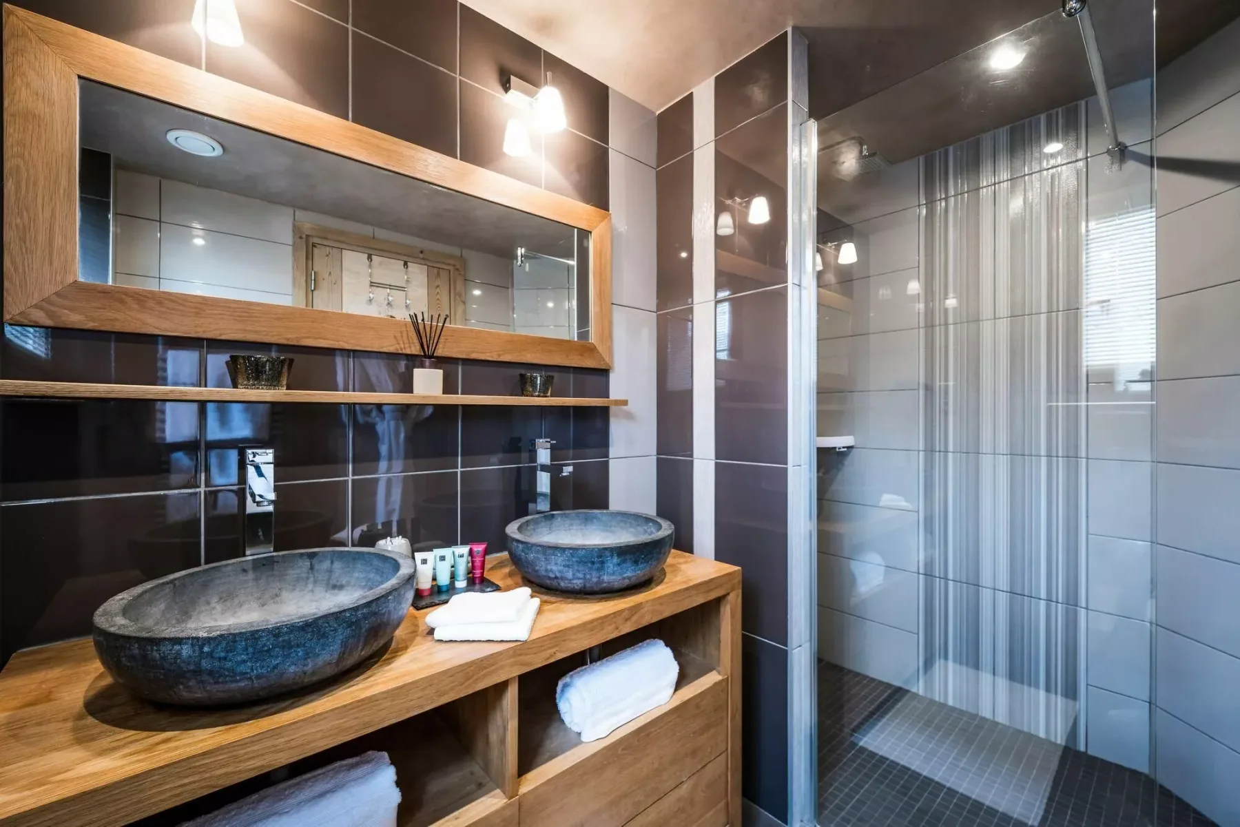 A modern bathroom with two vessel sinks and a glass-enclosed shower.