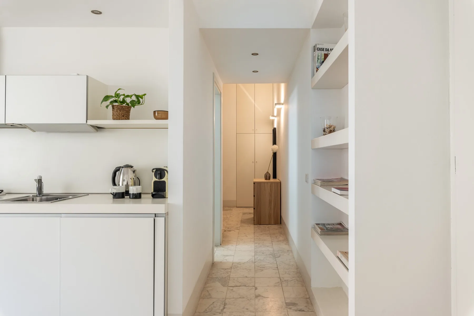 Una cocina compacta da a un pasillo con estanterías empotradas.