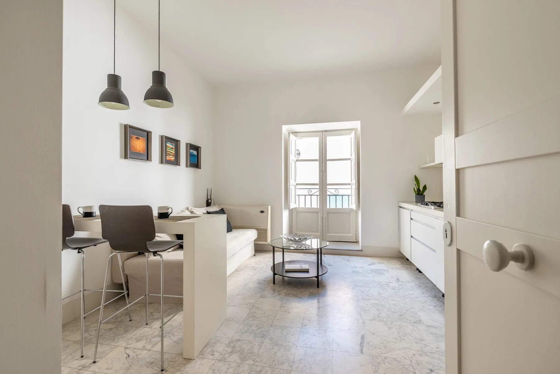 Una luminosa sala de estar y comedor con mesa, asientos y puertas de cristal.